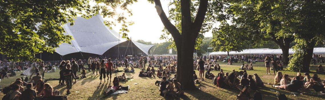 View of festival goers sitting on the grass at All Points East festival in Victoria Park